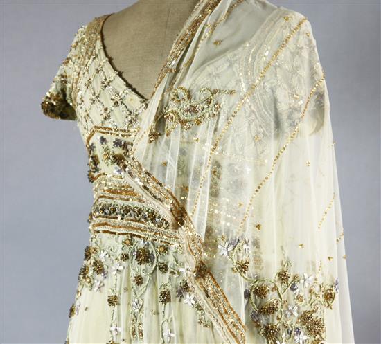A floor length cream net evening dress, heavily embroidered with silver and gold coloured thread,
